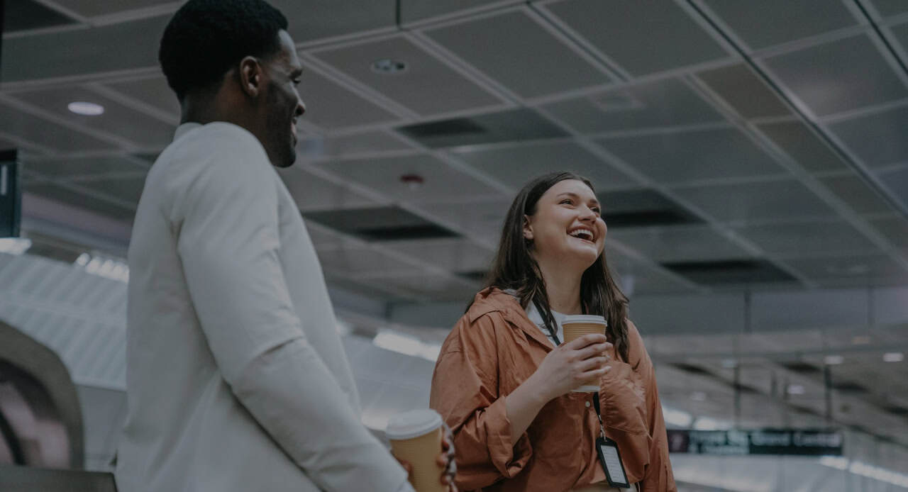 Young man and woman happily discussing a professional leadership program with coffee
