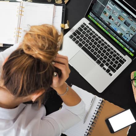 Shot from above of a frustrated woman working on a laptop for a professional leadership program