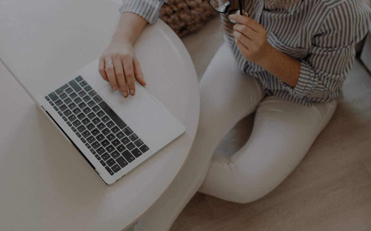 Woman holding glasses working on a professional leadership program on a laptop