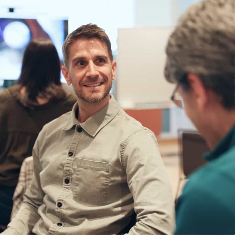 Professional young man smiling at a woman during group coaching