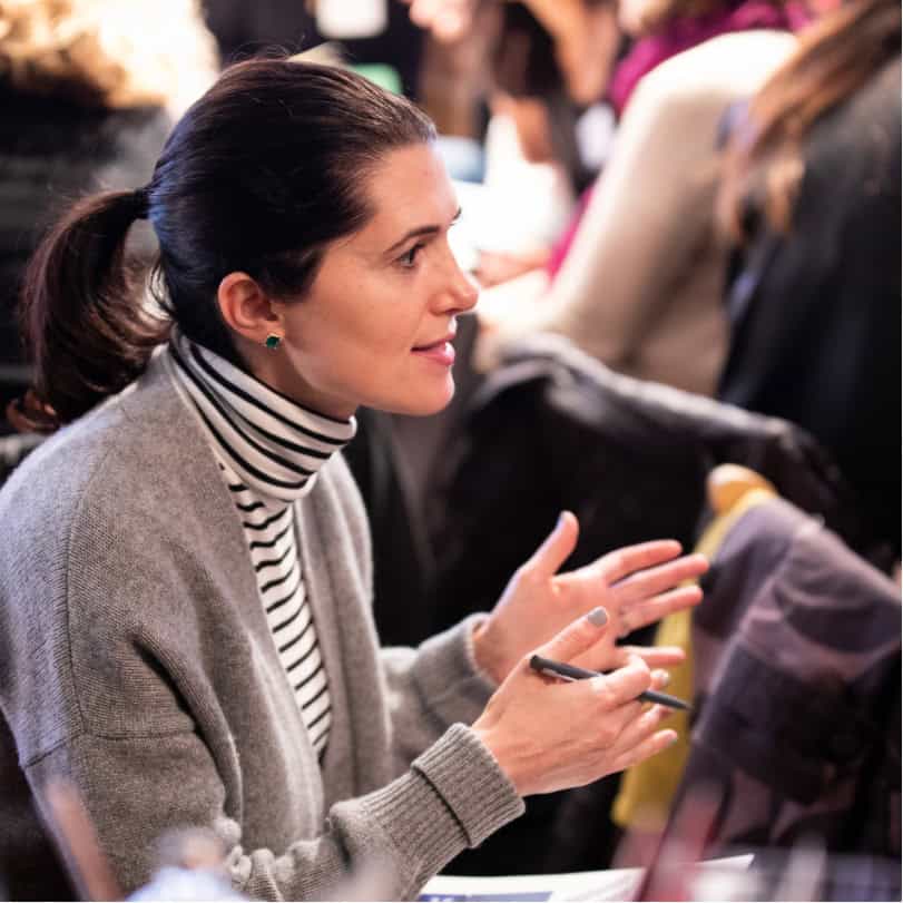 Young white woman in a sweater discussing leadership assessments with a group