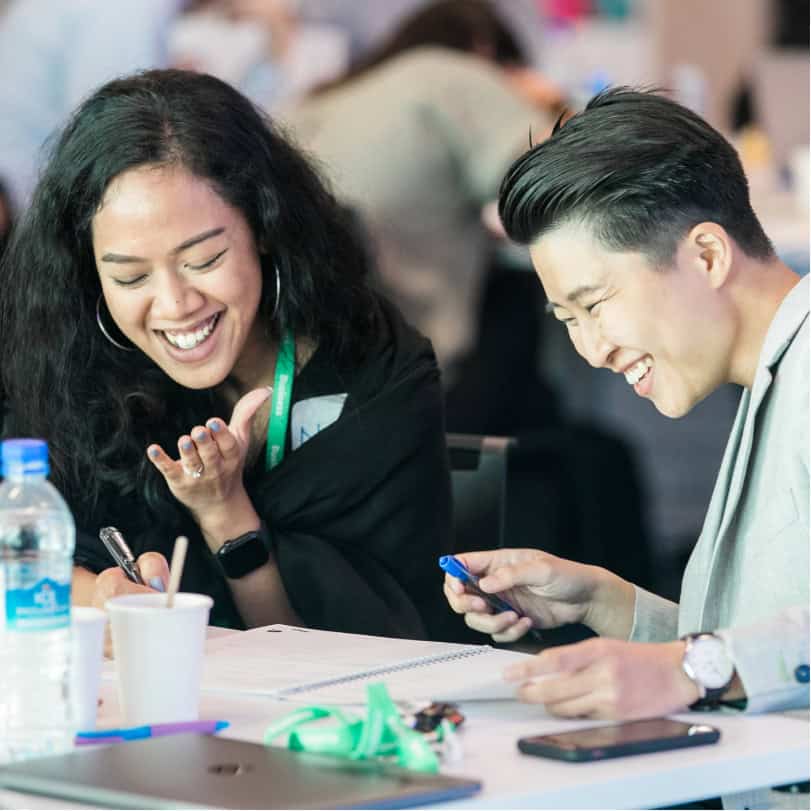 2 People smiling and taking notes for corporate training programs