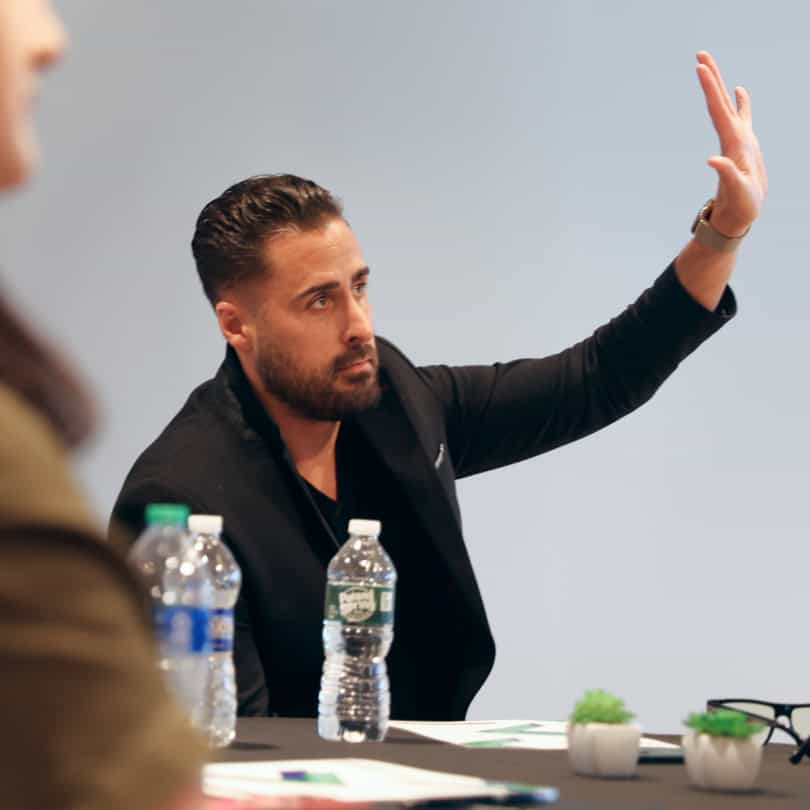 Man in a black suit raising his hand during team development training