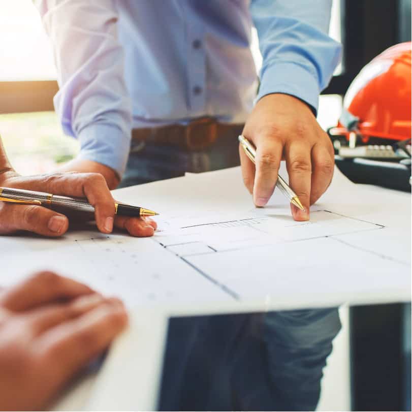 Man's hands pointing at blueprints and discussing professional development for engineers