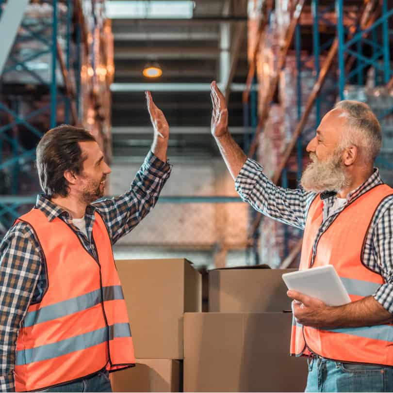 Two man in safety vests high-fiving about manufacturing workforce development