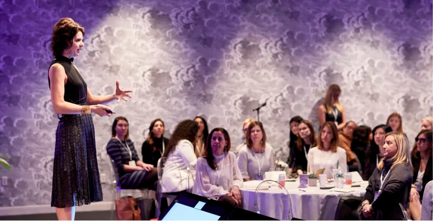 Woman discussing sales enablement training on a stage for a group