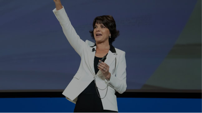 Woman in a white blazer on stage to lead a leadership development program